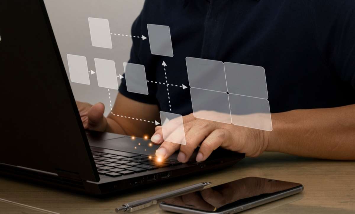 A smiling man working on a laptop with flowcharts, property management virtual assistant concept