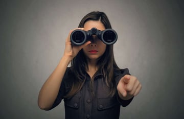 A woman looks through binoculars and points toward a virtual property management assistant for her team