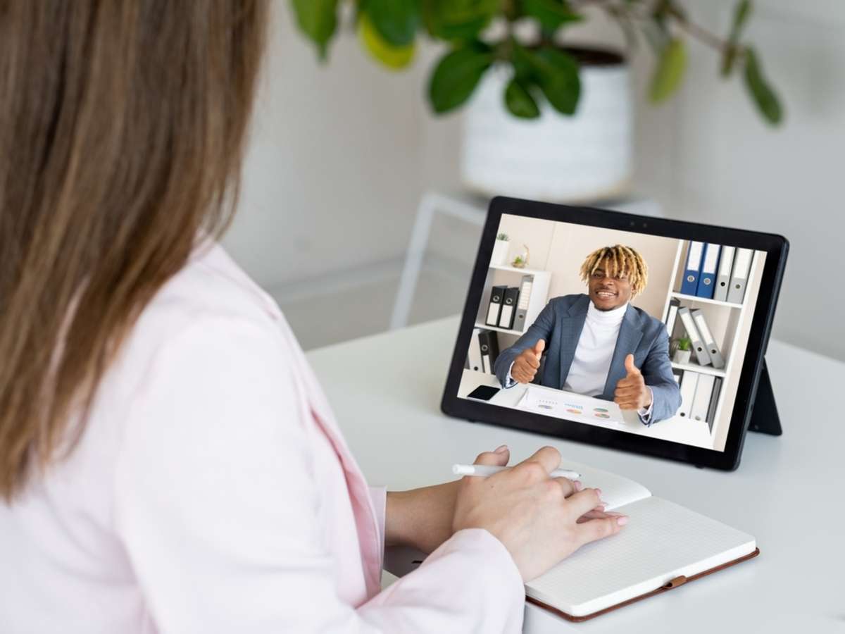 Female CEO discussing agreement with satisfied business partner showing deal gesture on tablet screen in digital office