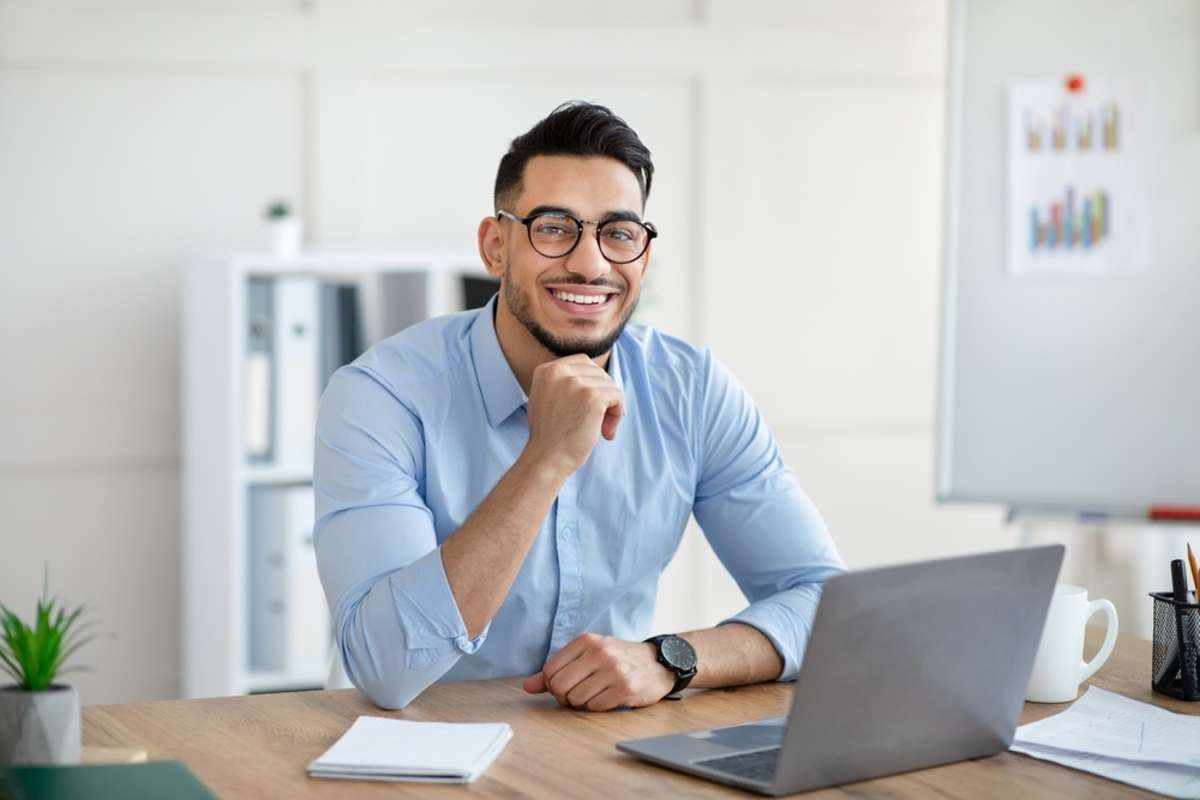 A smiling man using a laptop computer, remote assistant concept