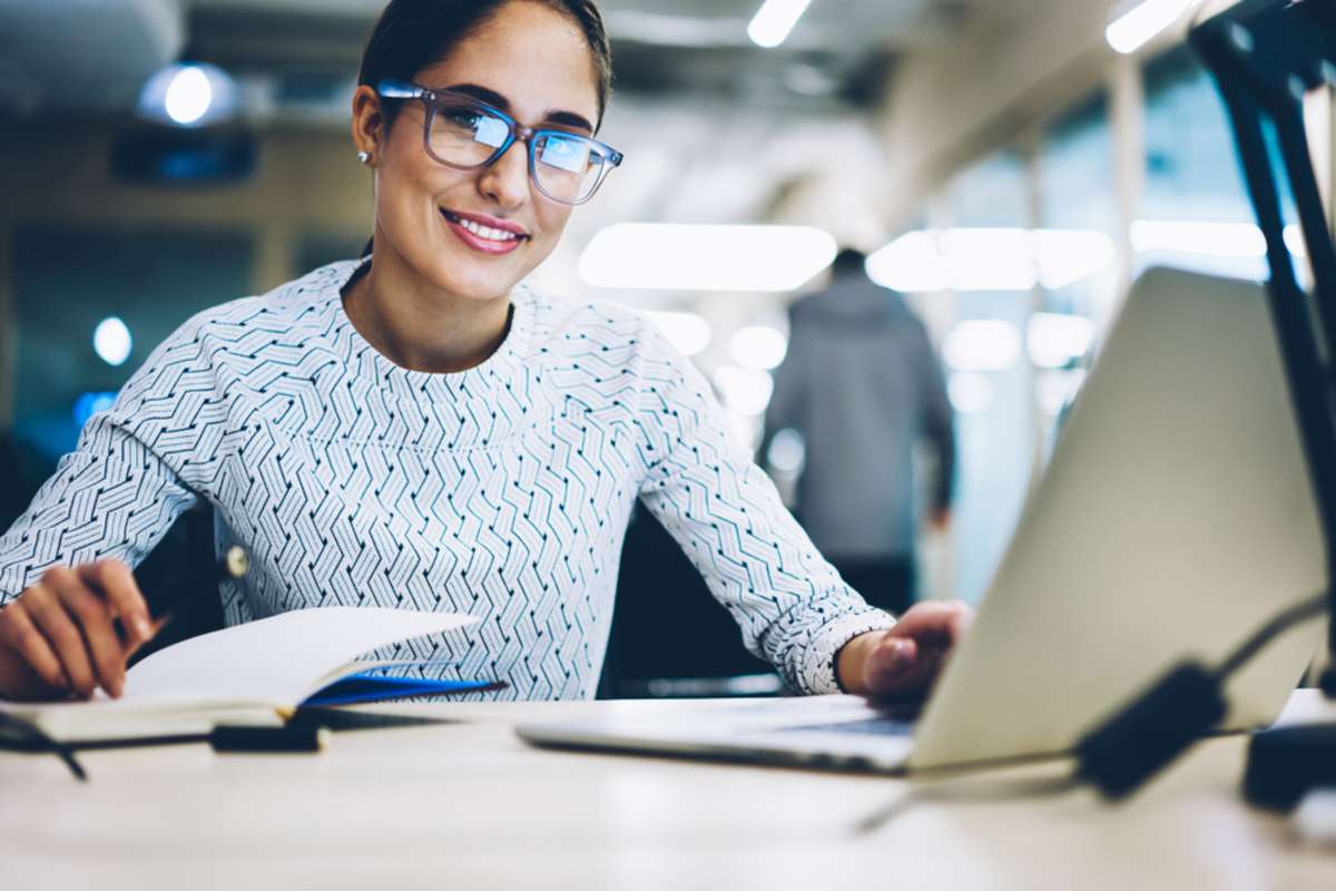 Portrait of prosperous business woman in spectacles providing protection while work on laptop computer looking at camera