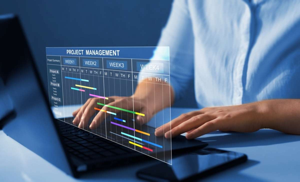 Project manager working on laptop and updating tasks and milestones progress planning with Gantt chart