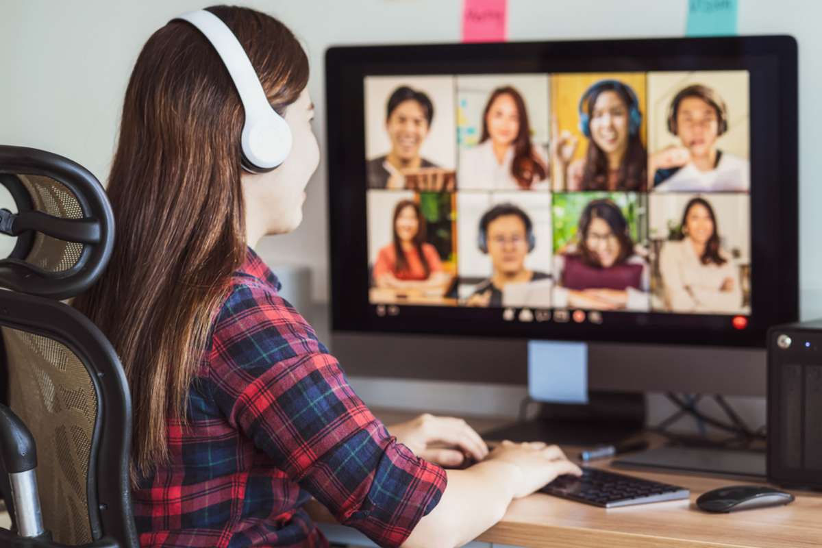 Rear view of Asian woman working and online meeting via video conference with colleague and team building when Covid-19 pandemic