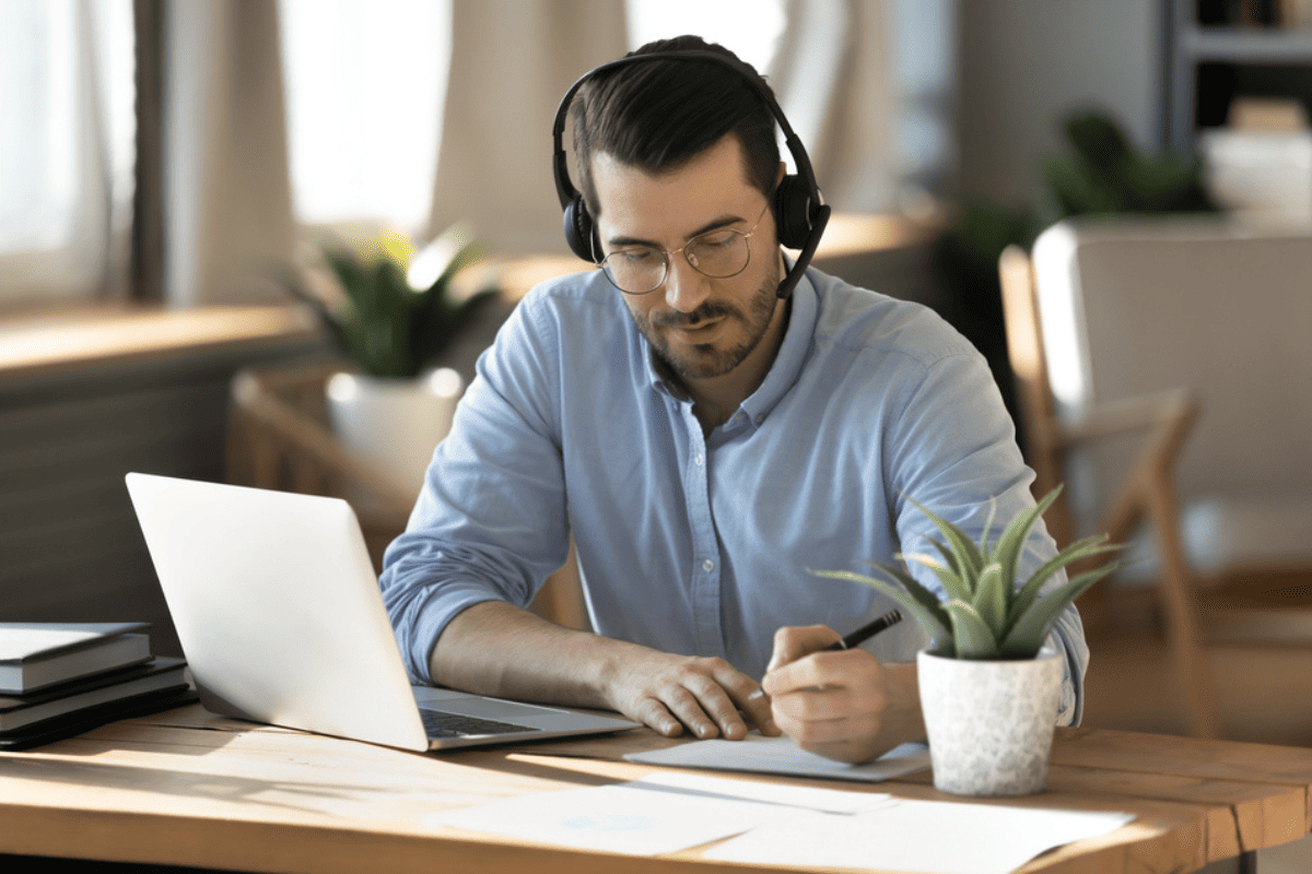 A man with a headset working on a laptop.